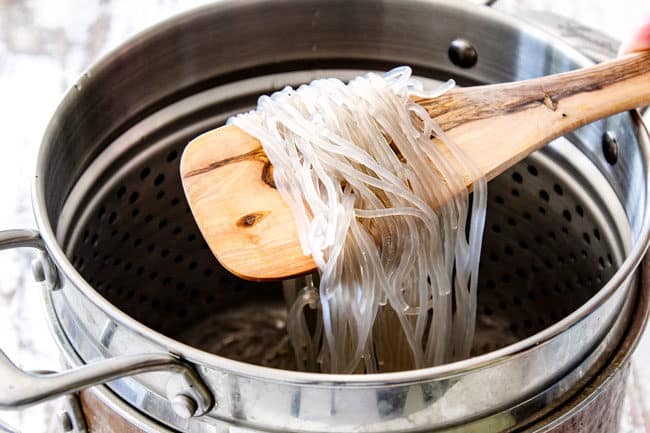 a wooden spoon holding up glass noodles showing how to make Korean Spicy Noodles