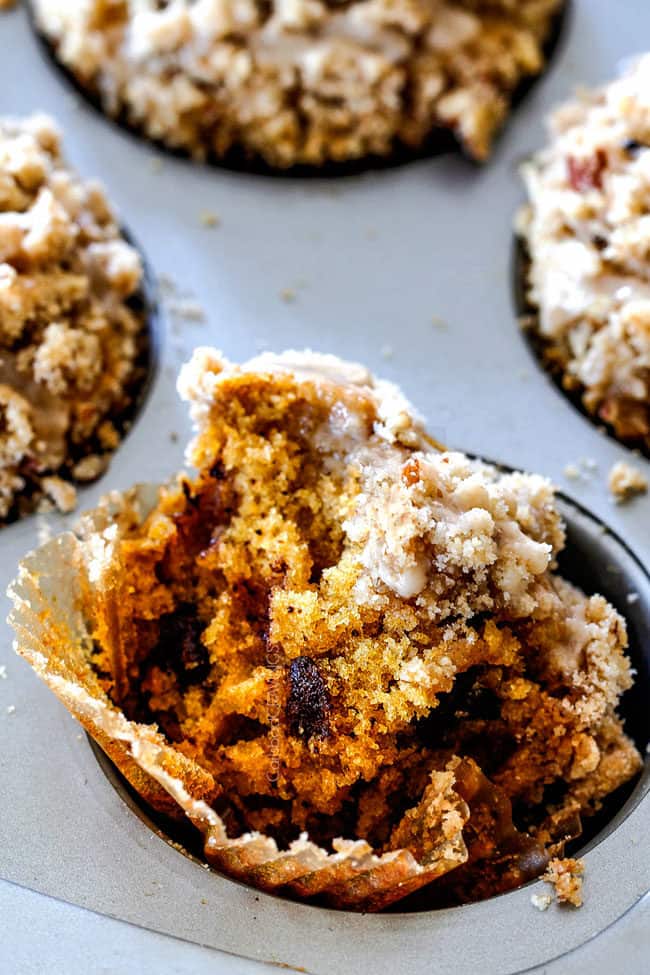 a half eaten chocolate chip pumpkin muffin in a muffin tin