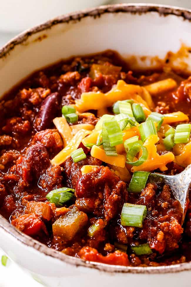 a spoonful of the best turkey chili with green onions and cheese