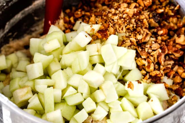 showing how to make poke cake by adding apples and walnuts to a bowl