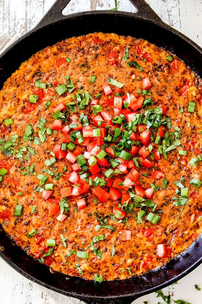 top view of queso fundido mexcano garnished with tomatoes, cilantro and green onions