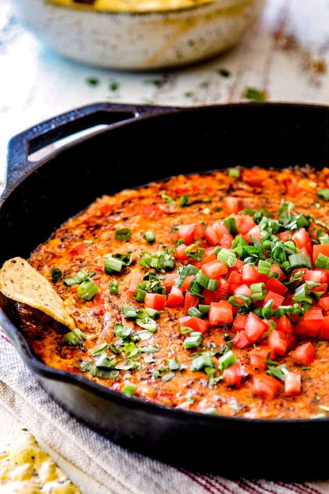 side view of easy Queso Fundido in a skillet with a tortilla chip for dipping