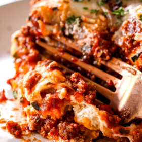 a fork cutting into a slice of classic lasagna