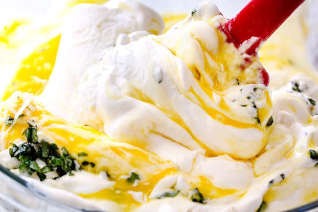 showing how to make manicotti filling by mixing together ricotta, mozzarella Parmesan, basil, egg and nutmeg in a glass bowl