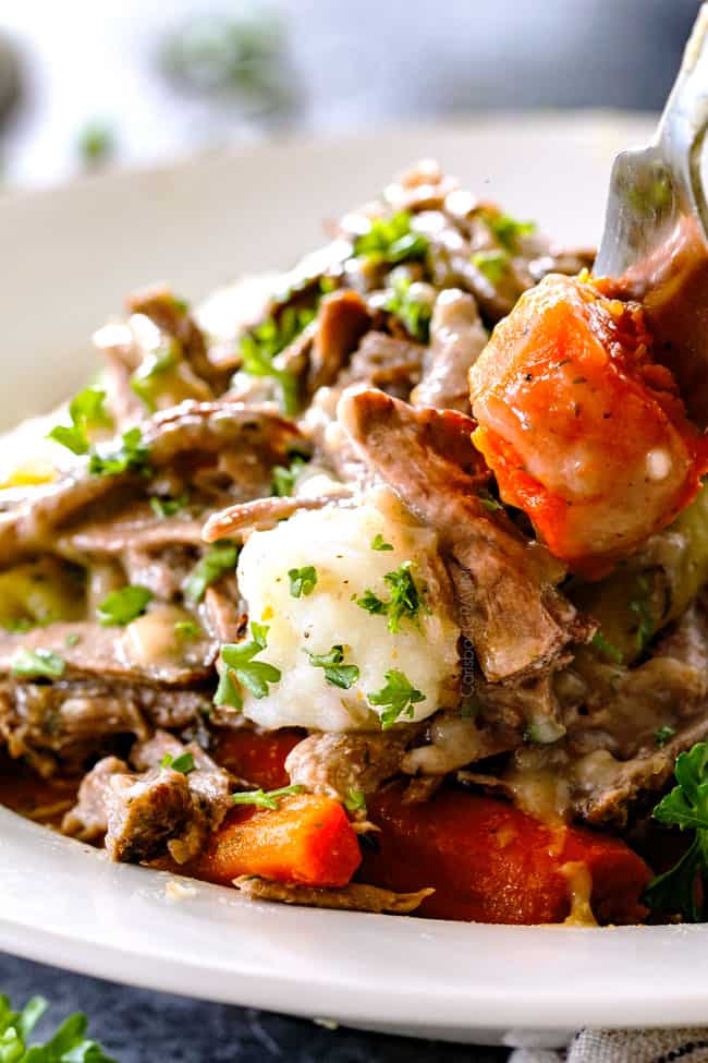 taking a bite of Mississippi Pot Roast with potatoes, carrots and gravy on a fork