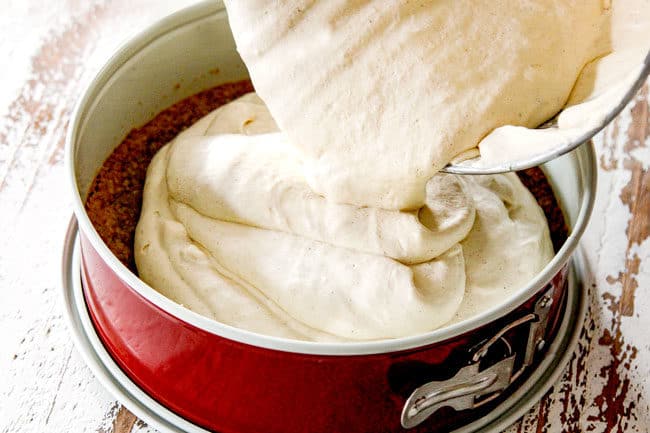 showing how to make pecan pie cheesecake by adding cheesecake filling to baked graham cracker crust