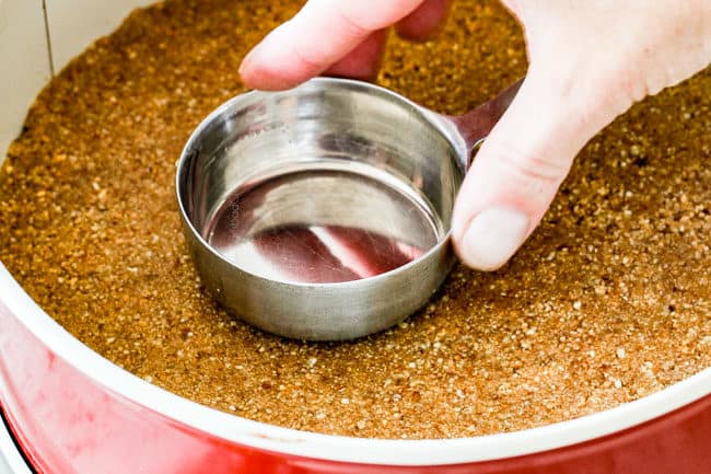 showing how to make pecan pie cheesecake by firmly pressing graham cracker crust into bottom of springformpan