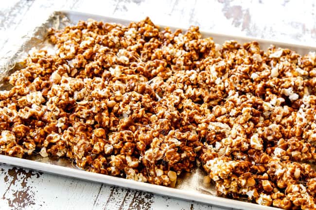 showing how to make caramel popcorn by spreading caramel covered popcorn out on a baking tray before going into the oven
