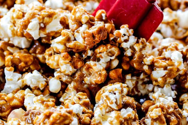 showing how to make caramel popcorn by stirring air popped popcorn with caramel