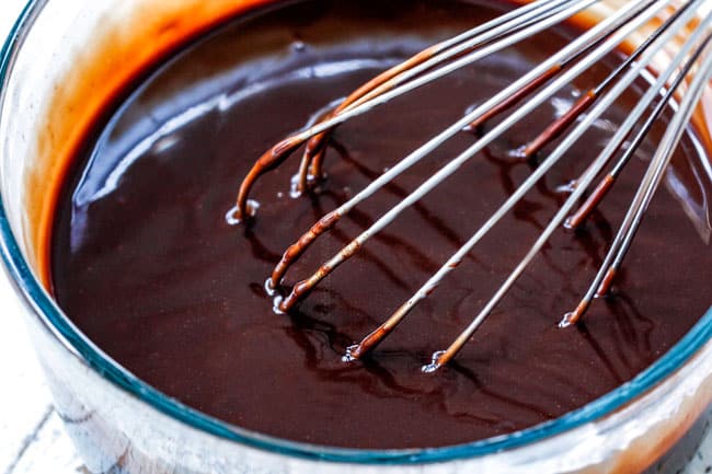 showing how to make Chocolate Eclair Cake by whisking chocolate and heavy cream together to make chocolate ganache