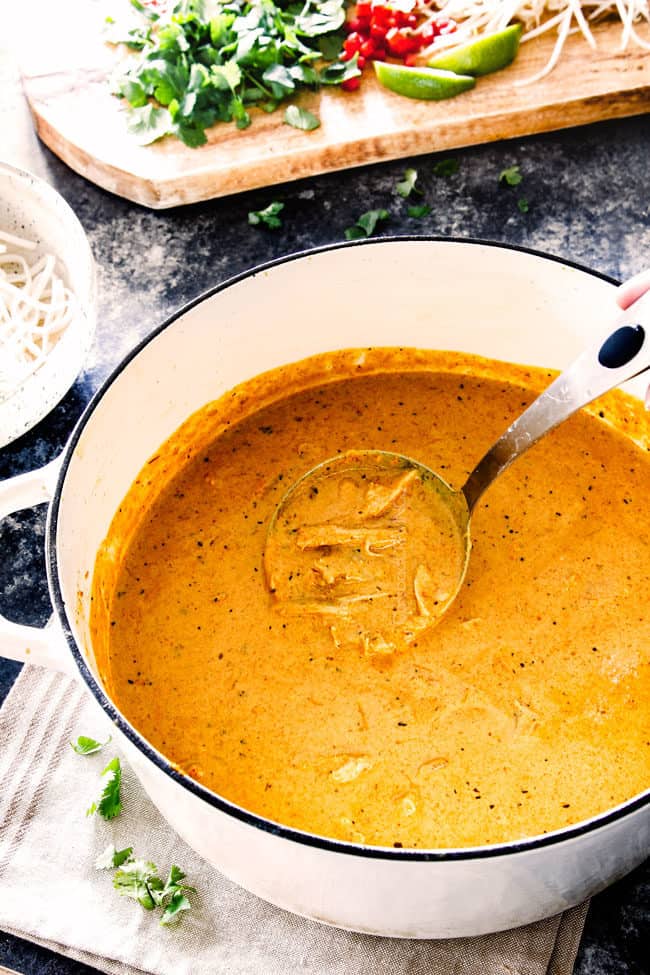 authentic laksa in a white pot with chicken with a bowl of rice noodles nearby