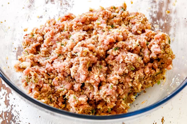 showing how to make the filling for potstickers by mixing ground pork, Napa cabbage, green onions, garlic, ginger, shiitake mushrooms, soy sauce, sesame oil in a glass bowl