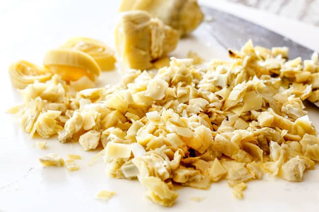 showing how to make spinach artichoke dip by chopping artichokes