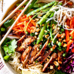 top up close view of Vietnamese noodle with rice noodles, lemongrass chicken, shredded carrots, julienned carrots, bean sprouts and snow peas