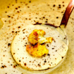 up close of a ladle full of creamy Cauliflower Soup in the pot