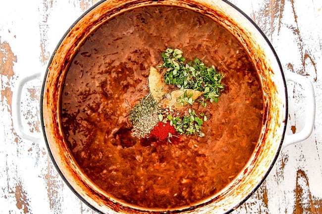 showing how to make French Onion Soup by adding thyme, beef broth and seasonings to the soup