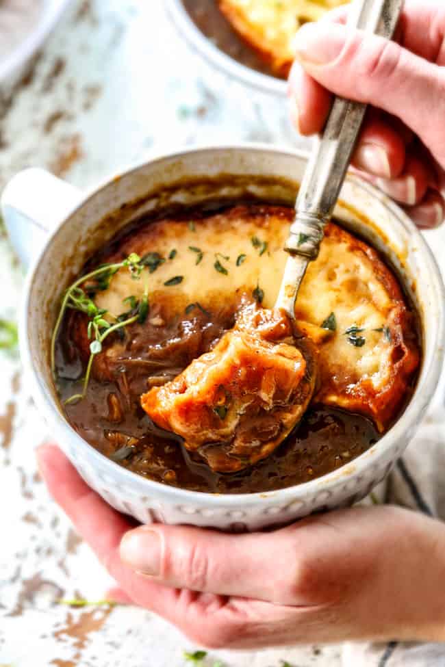 two hands holding a bowl of classic French Onion Soup