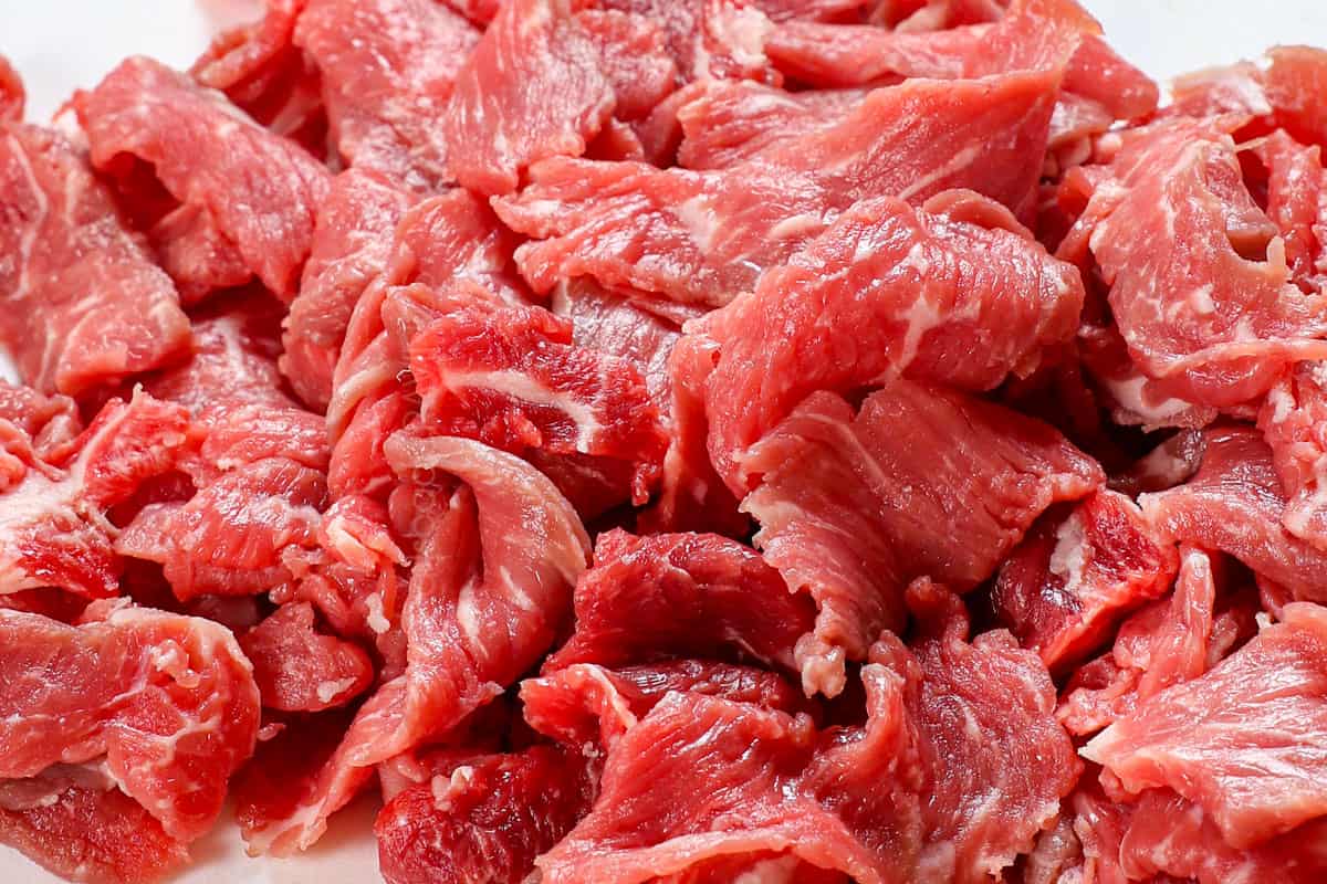 showing how to make Philly cheesesteak by slicing the meat as thinly as possible