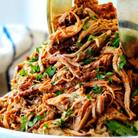 two tongs picking up some slow cooker pork for pork fajitas recipe