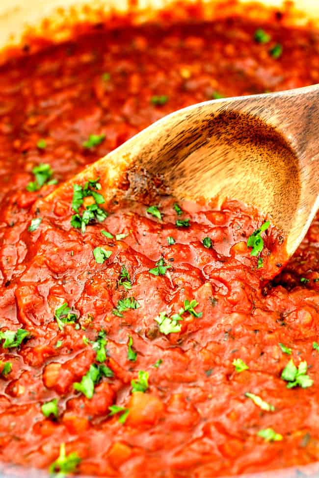 a wooden spoon in a big bowl of homemade marinara sauce