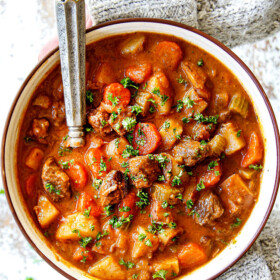 two hands holding a bowl of old fashioned beef stew showing what's in it: beef, potatoes, carrots, celery, onions, garlic, gravy