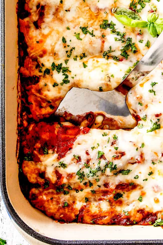 up close of a silver spatula digging into a big dish of cheese manicotti