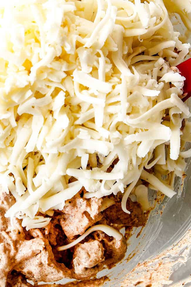 showing how to make chicken enchiladas by adding cheese to chicken in a glass bowl