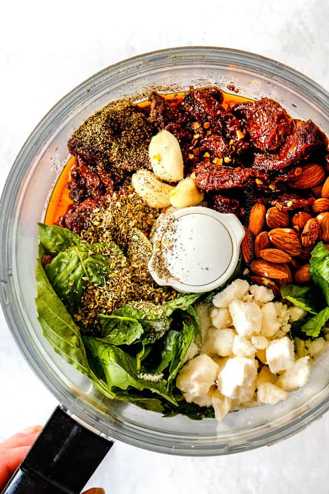 showing how to make Greek Salad Dressing by adding red wine vinegar, sun dried tomatoes, lemon juice, oregano, red pepper flakes to food processor