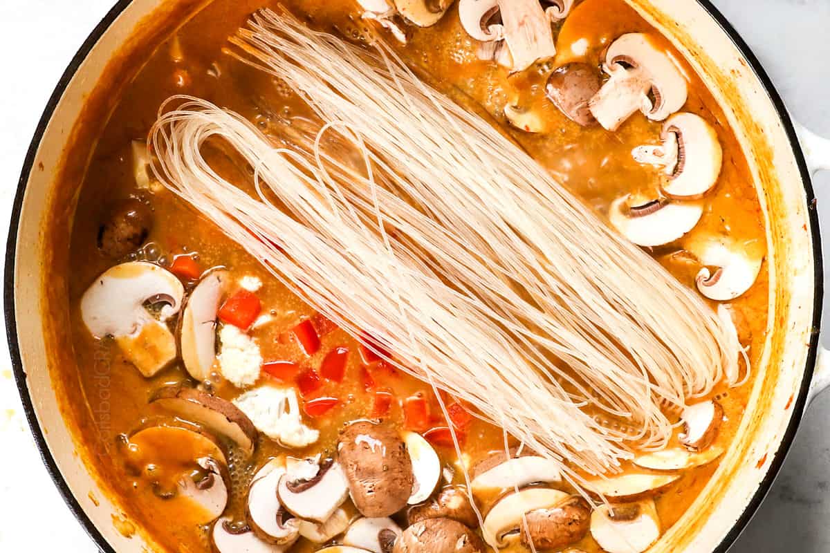 showing how to make Thai chicken soup by adding rice noodles, mushrooms, cauliflower and bell peppers to the pot