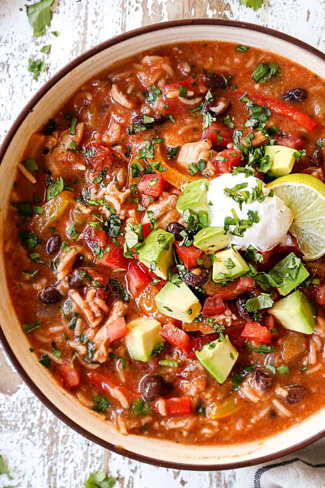 top view of a bowl of chicken fajita soup garnished with tomatoes, avocados, cilantro and sour cream