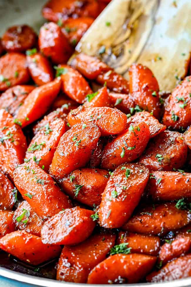 glazed carrots recipe in a stainless steel skillet with a wooden spoon