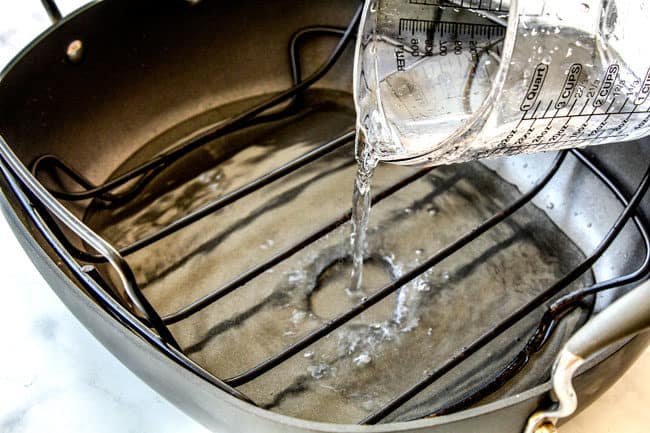 showing how to bake ham by adding water to the bottom of a roasting pan