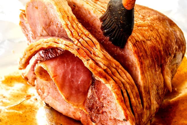 showing how to make honey baked ham by brushing honey glaze all over ham