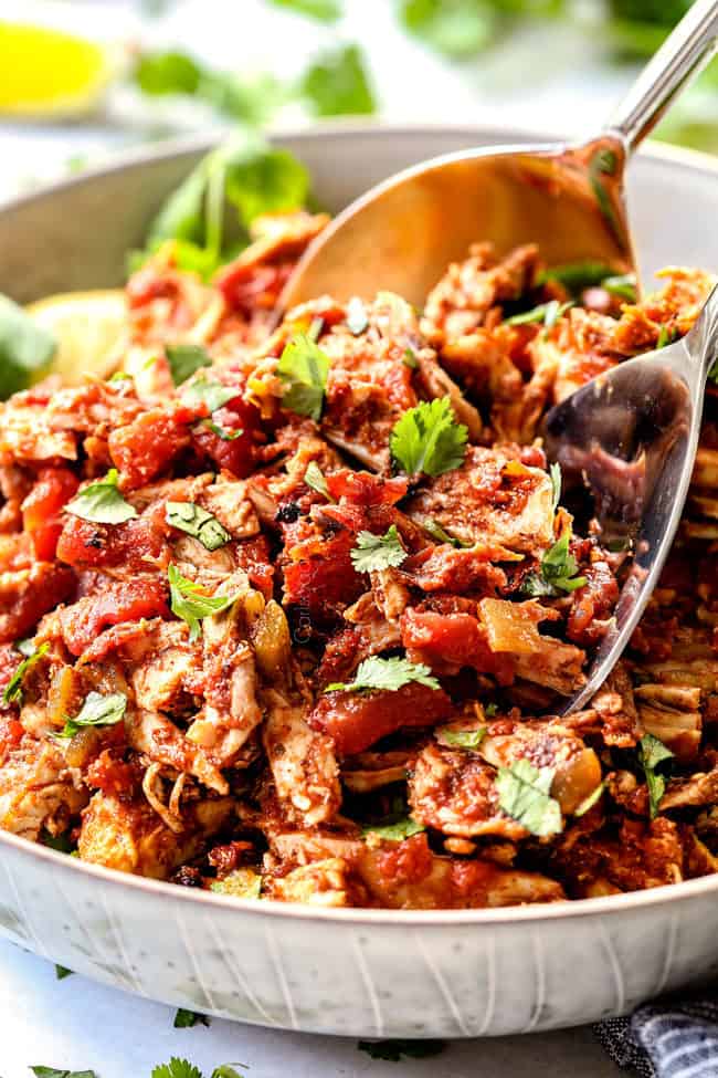 two tongs picking up juicy Mexican chicken