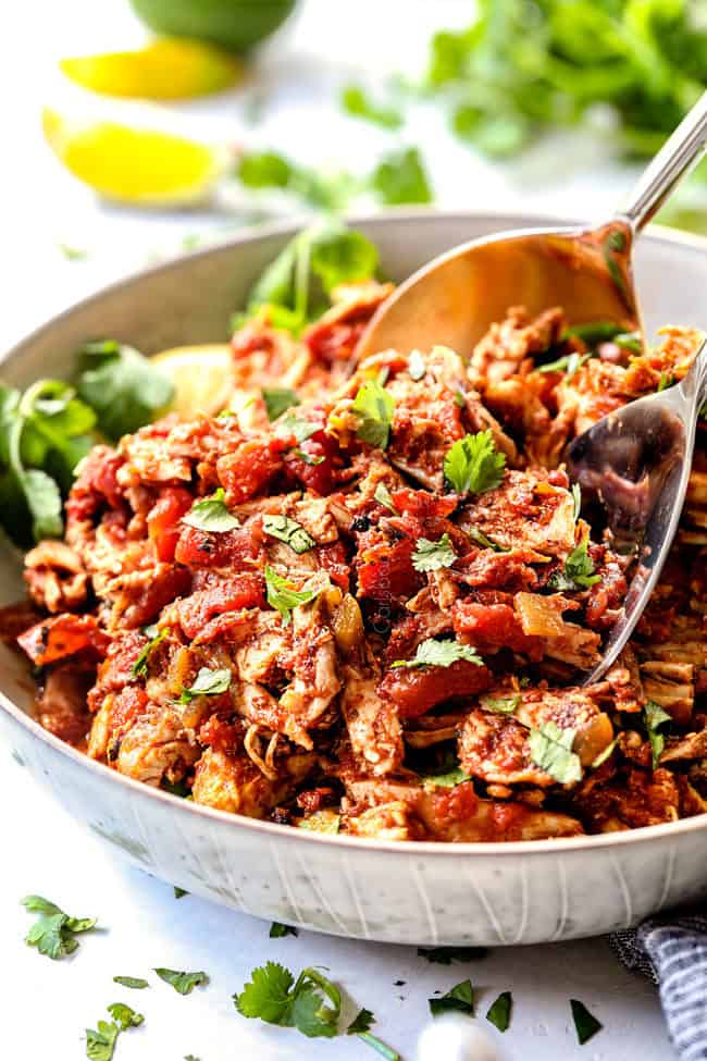 two tongs picking up juicy Mexican chicken