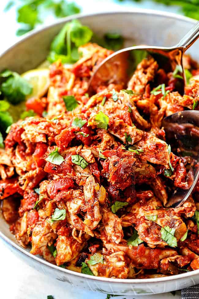 two tongs picking up juicy Mexican chicken