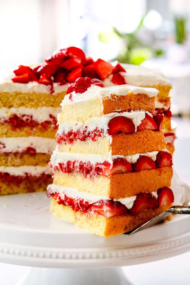 taking a slice of showing how to layer strawberry shortcake cake by