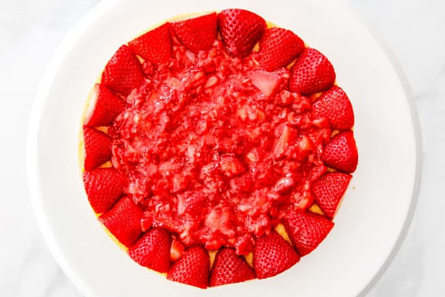 showing how to layer strawberry shortcake cake by adding chopped strawberries to the center of the cake eayer