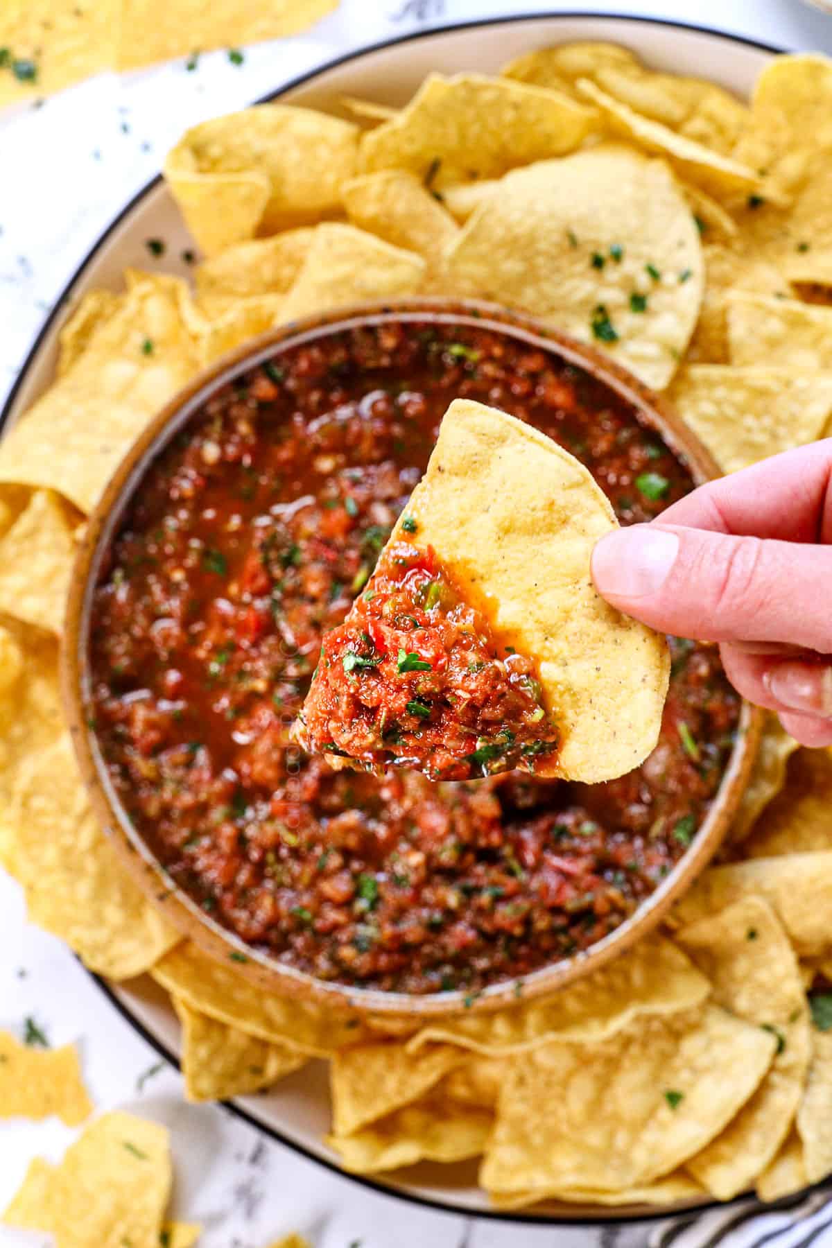 holding up chip with salsa on it to show the fresh salsa recipe