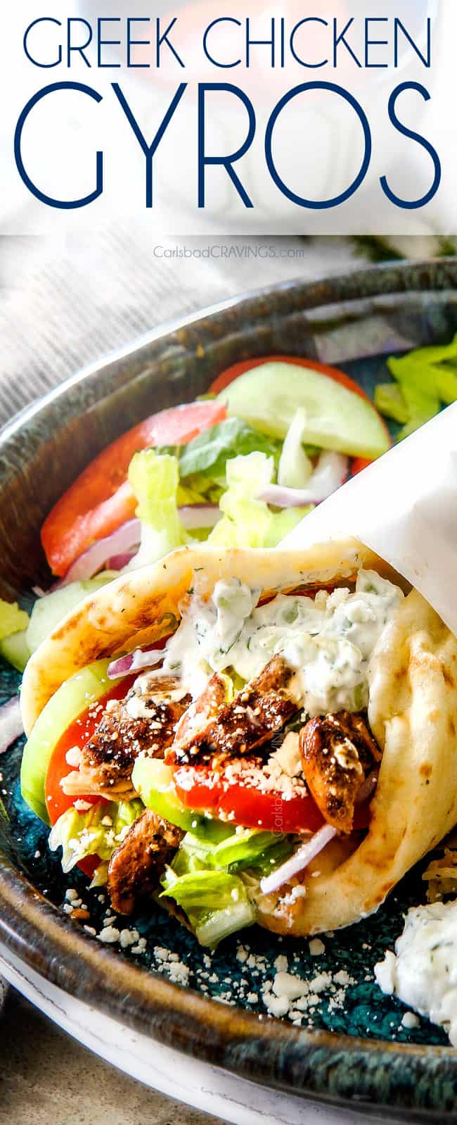 up close of a chicken gyro with Greek chicken, tomatoes, lettuce and tzatziki wrapped in paper