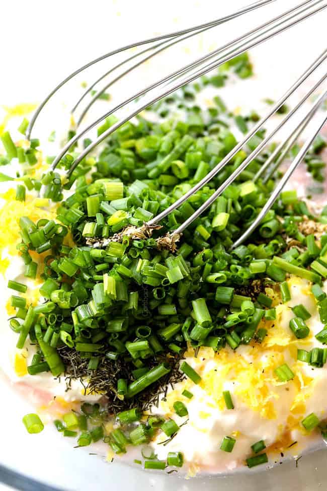 showing how to make cucumber salad with mayo by making cucumber salad dressing with sour cream, mayonnaise, dill, chives, garlic, lemon juice