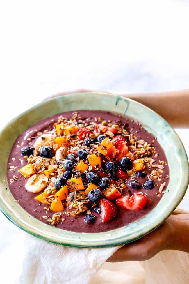 two hands holding out acai bowl