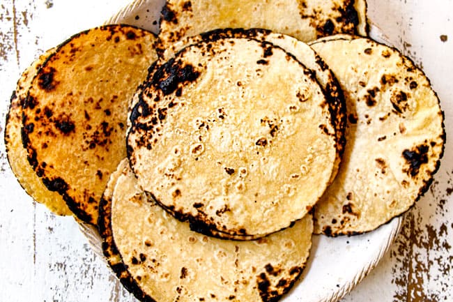 showing how to make shrimp taco recipe by warming charring corn tortillas