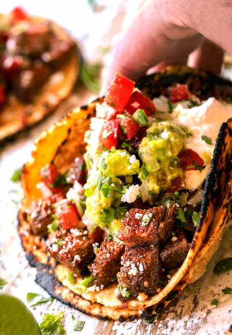 a hand holding a carne asada street taco ready to eat