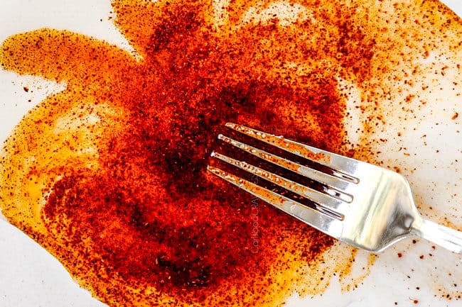 showing how to elote by adding vegetable oil, salt and chili powder to a plate to brush on Mexican corn