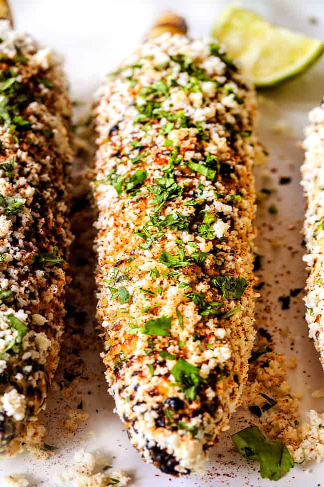 front up close view of elote Mexicano with mayonnaise, sour cream, cilantro, lime and queso fresco