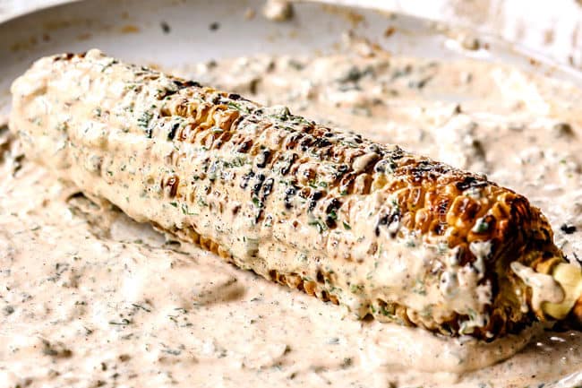 showing how to make elote by smothering in mayonnaise cream sauce