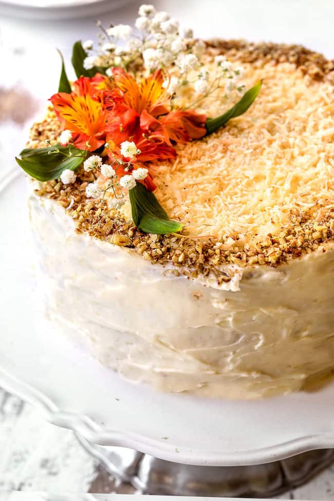 showing how to decorate hummingbird cake recipe with coconut and pecans on top of cake with flowers