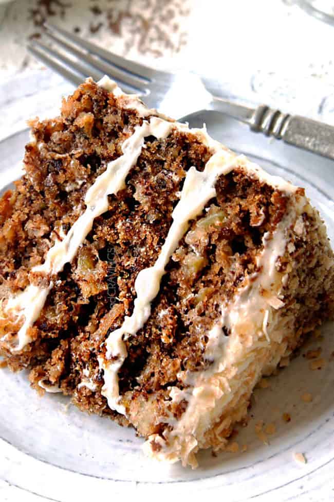 easy hummingbird cake on a white plate with cream cheese frosting, bananas, pineapple, pecans coconut