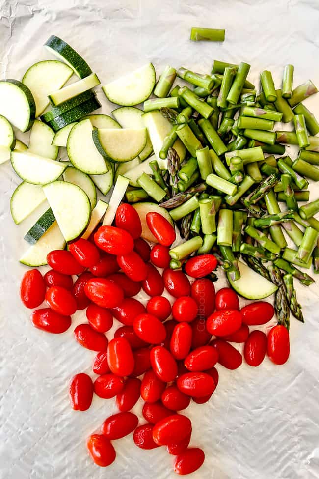 showing ingredients for lemon chicken pasta with tomatoes, zucchini an asparagus on a cutting board